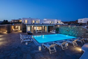 A poolside area with lounge chairs and a stone wall.