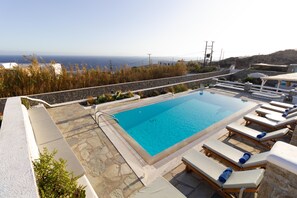 A rooftop pool with clear blue water, surrounded by lounge chairs and a stone deck.