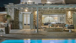 A stone building with a pool, outdoor seating, and a covered patio area. - Villa Mando (Mykonos)