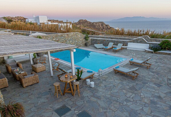 A pool area with lounge chairs and a stone patio.