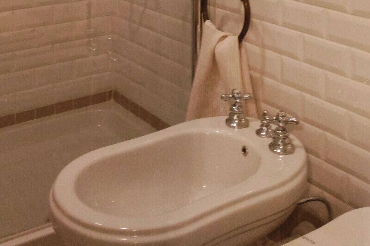 A bathroom with a shower, a sink, and a framed picture on the wall.