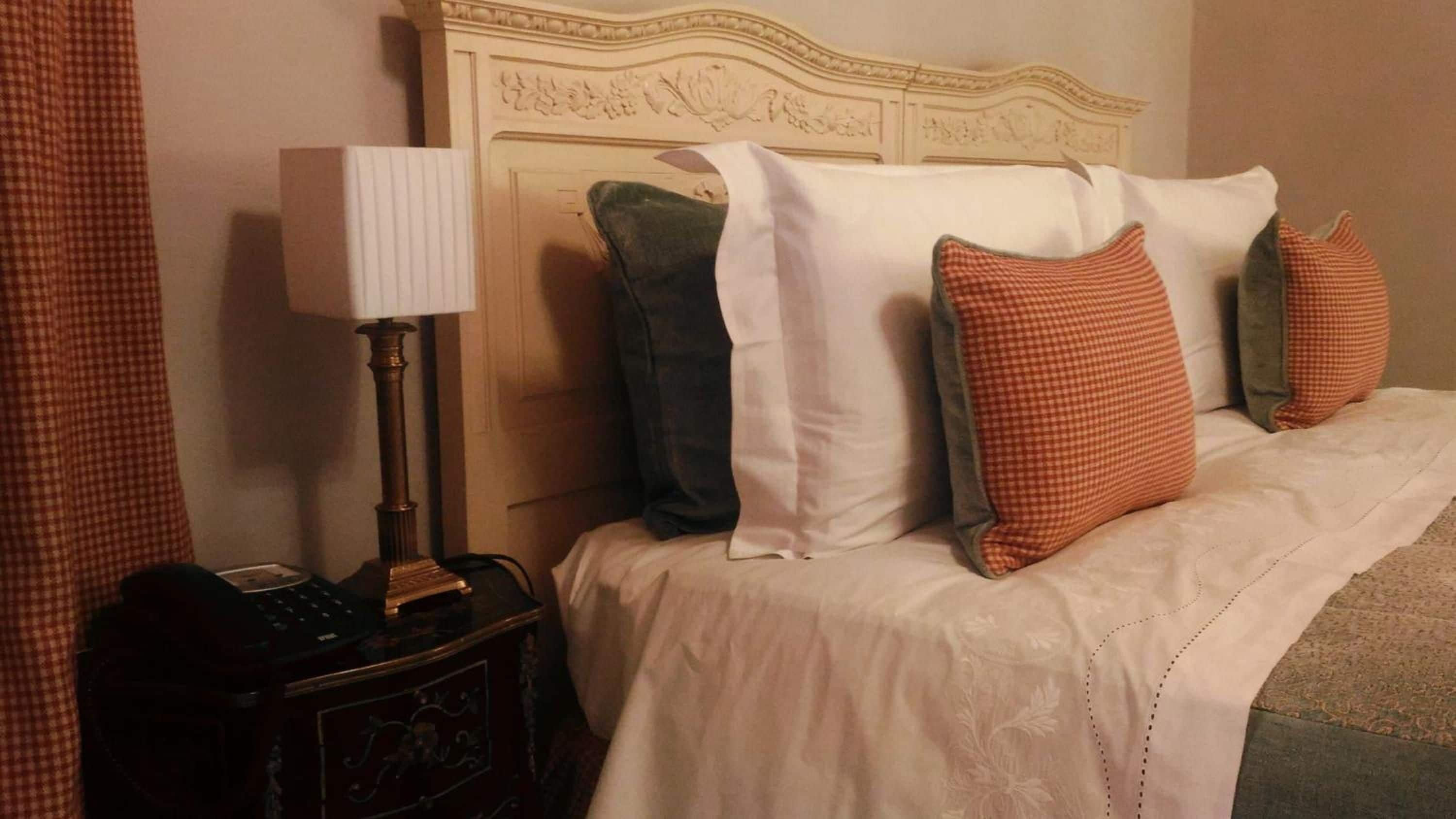 Une chambre d’hôtel avec un lit, des oreillers, une lampe de chevet et une table de chevet.