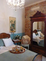 Una habitación de hotel con una cama, un aparador de madera, un espejo, una araña y un cuadro en la pared.