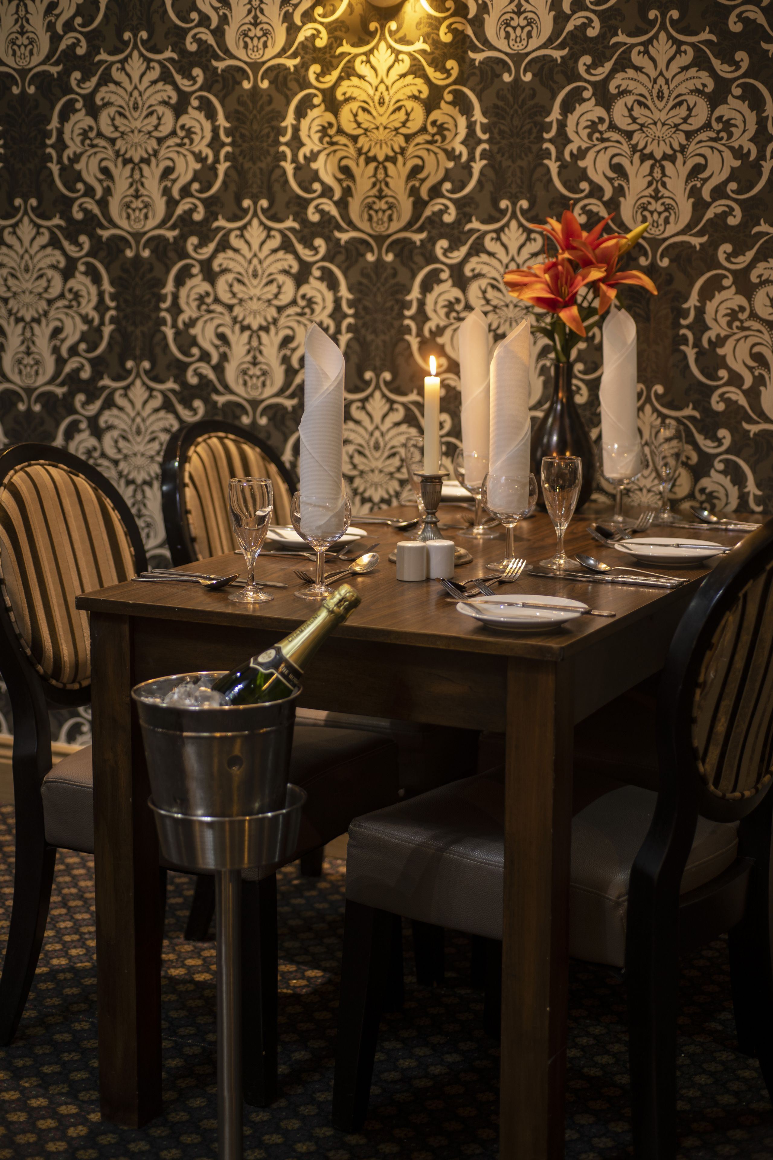 A formal dining table set with white napkins, candles, and a vase with flowers.