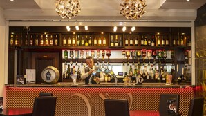 A bar area with a bartender, a variety of liquor bottles, and a patterned carpet. - Wessex Hotel (Street)
