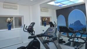 A gym with treadmills, a water bottle, and a vase with flowers on the windowsill. - Wessex Hotel (Street)
