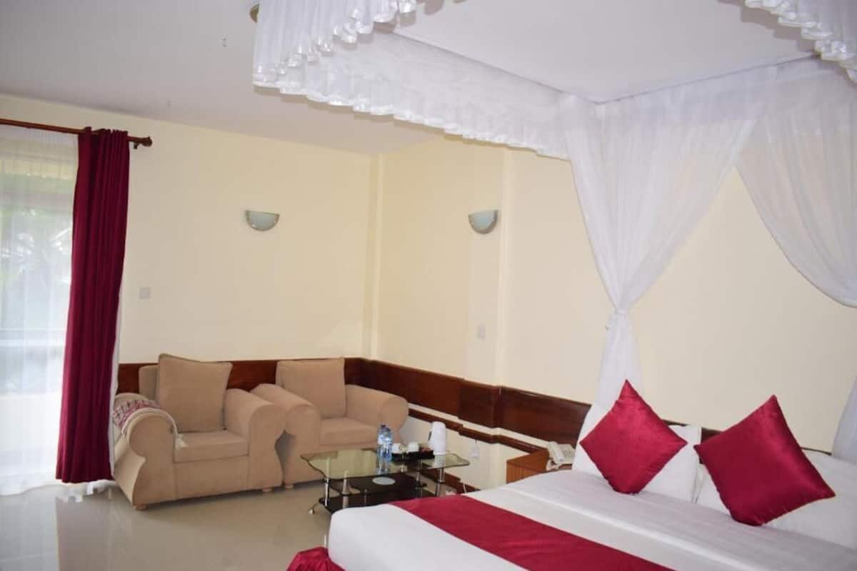 Una habitación de hotel con una cama, un sofá, una mesa de vidrio y una mesita de noche.