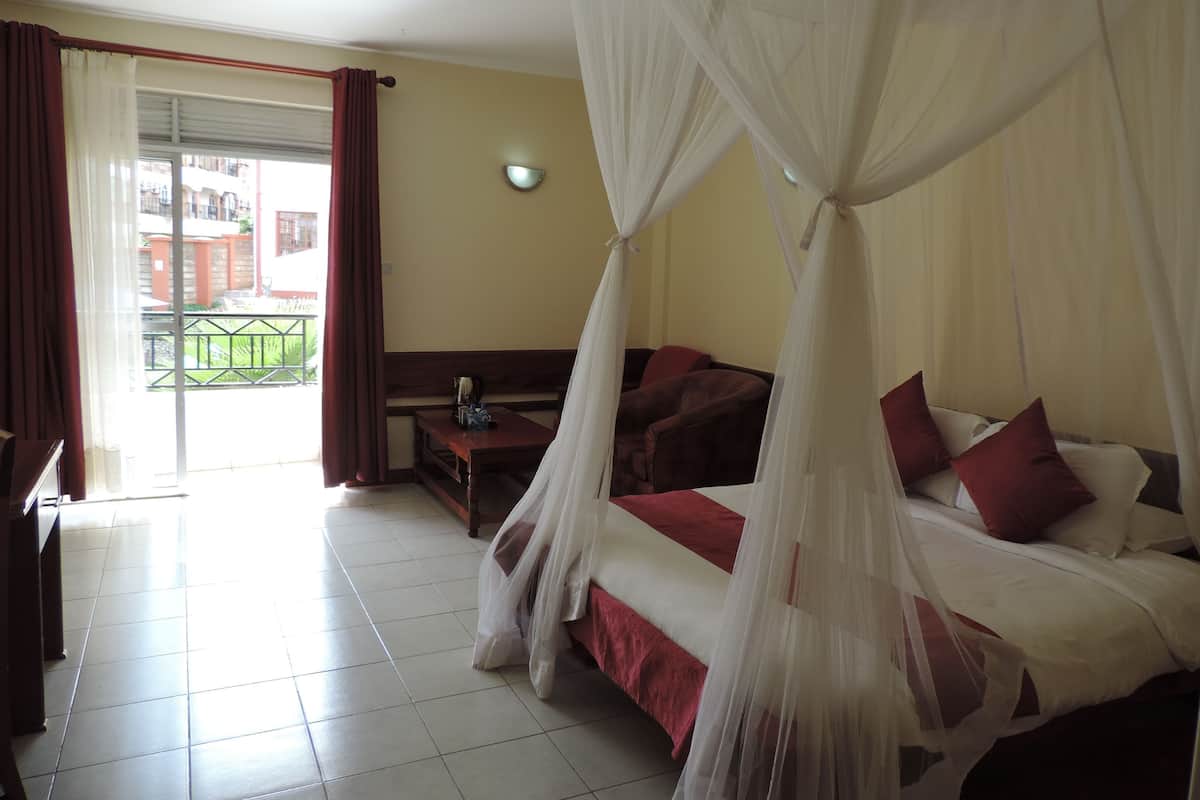 Una habitación de hotel con cama, escritorio, silla y vista al exterior.