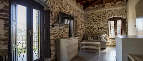 Junior suite, balkon | Woonkamer | Een flatscreentelevisie en een open haard