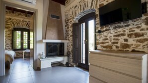 Een kamer met een stenen muur, een open haard, een televisie en een bed.