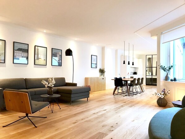 A modern living room with a sofa, a coffee table, and a dining area with chairs and a table.