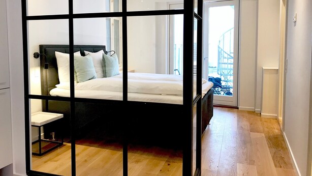 Un dormitorio moderno con una cama grande, una mesita de noche y vistas al balcón exterior.