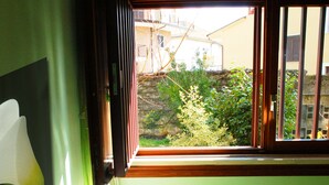 Ein Zimmer mit einem Bett, einem Fenster und Blick auf Grünfläche.