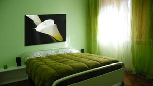 Ein Bett mit einer grünen Stegdecke, einem weißen Kopfkissen und einem Schwarz-Weiß-Gemälde an der Wand.