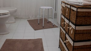 Ein Badezimmer mit weißen Sanitärobjekten, einem Korbschrank und einem braunen Teppich.