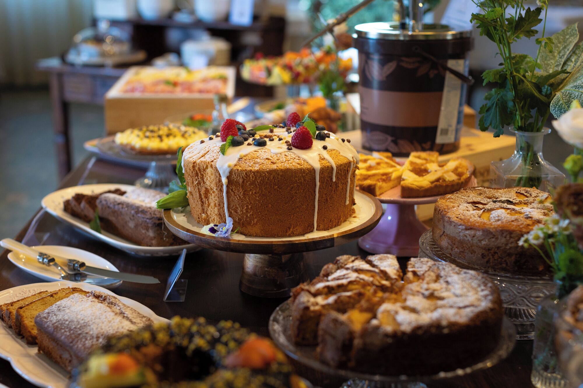 A buffet table with various desserts including a cake with white icing and fruit, and other baked goods.