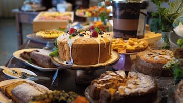 Ein Buffet mit verschiedenen Desserts, darunter ein Kuchen mit weißem Zuckerguss und Früchten, sowie weitere Backwaren.