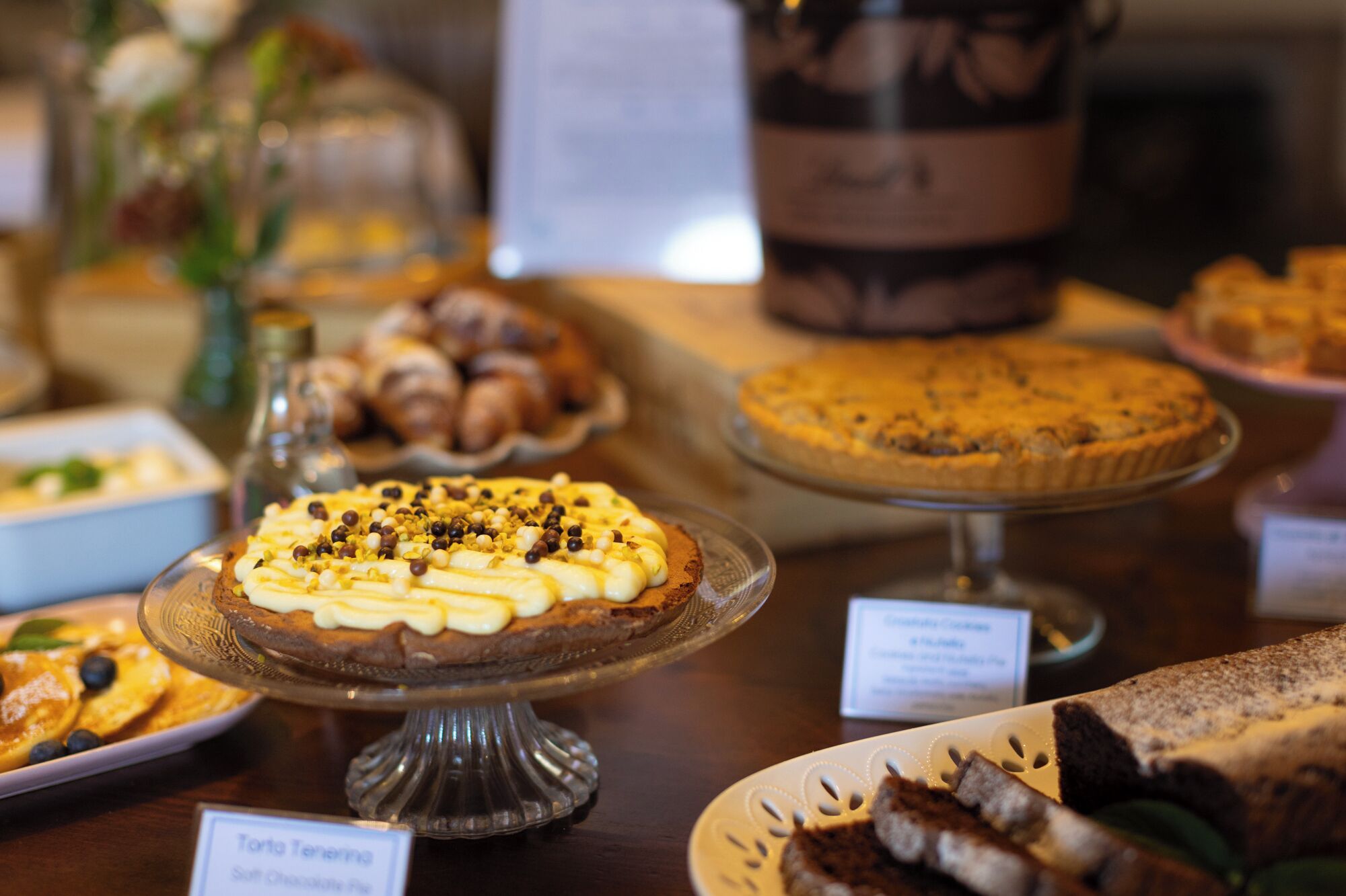 A variety of desserts on display, including a pie with a golden crust and a tart with a creamy topping.