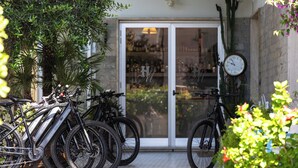 Bicycles parked outside a building with a glass door, a clock on the wall, and potted plants. - Hotel Massimo (Cecina)