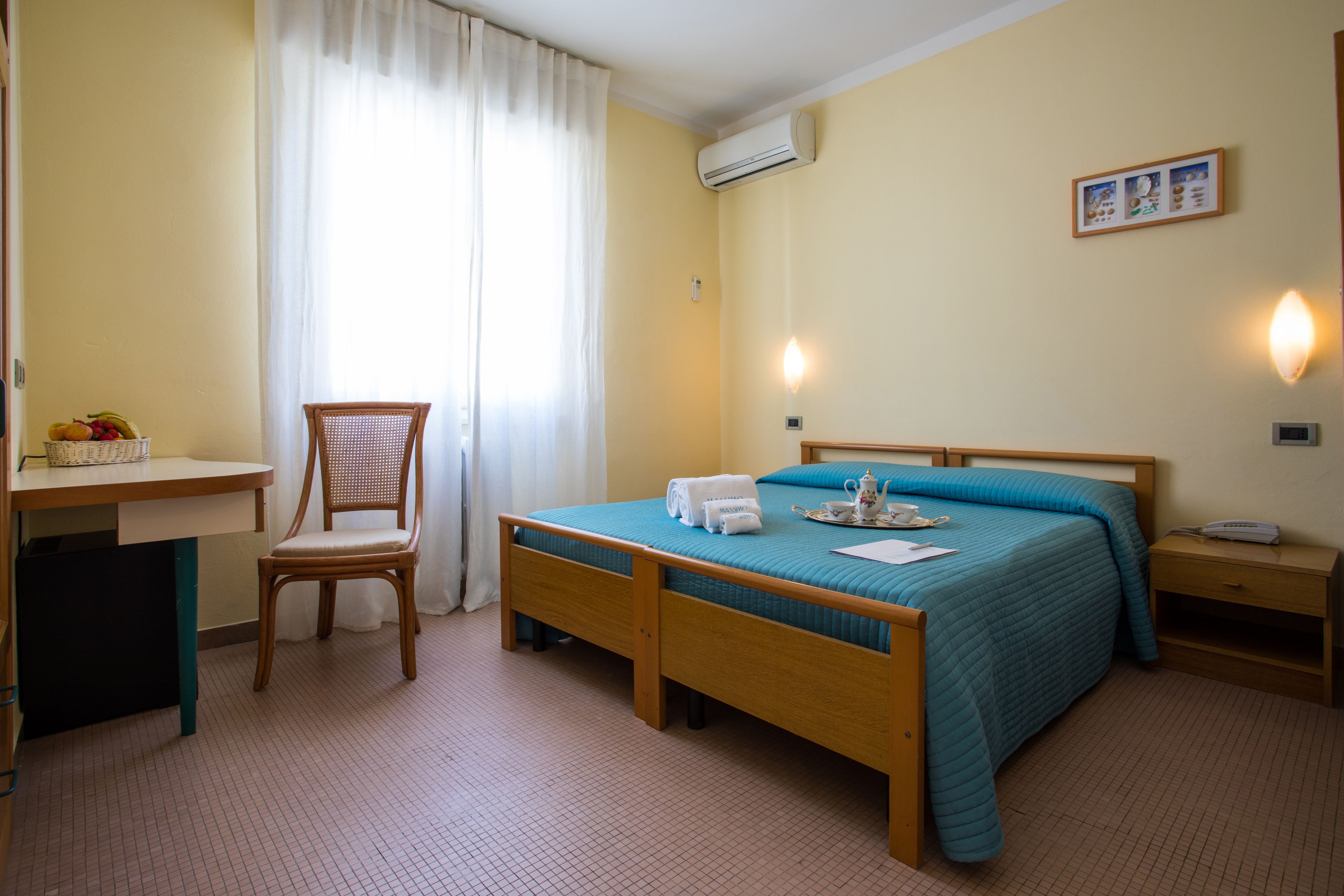 A bedroom with a bed, a chair, a desk, and a small table.