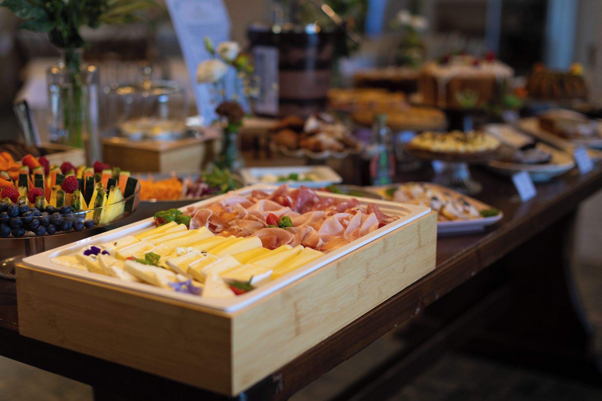 A buffet with various food items including fruits, cheeses, and meats.