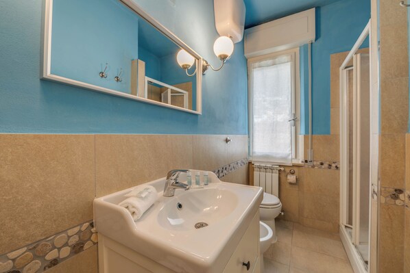 A bathroom with a sink, mirror, and toilet. - Hotel Massimo (Cecina)