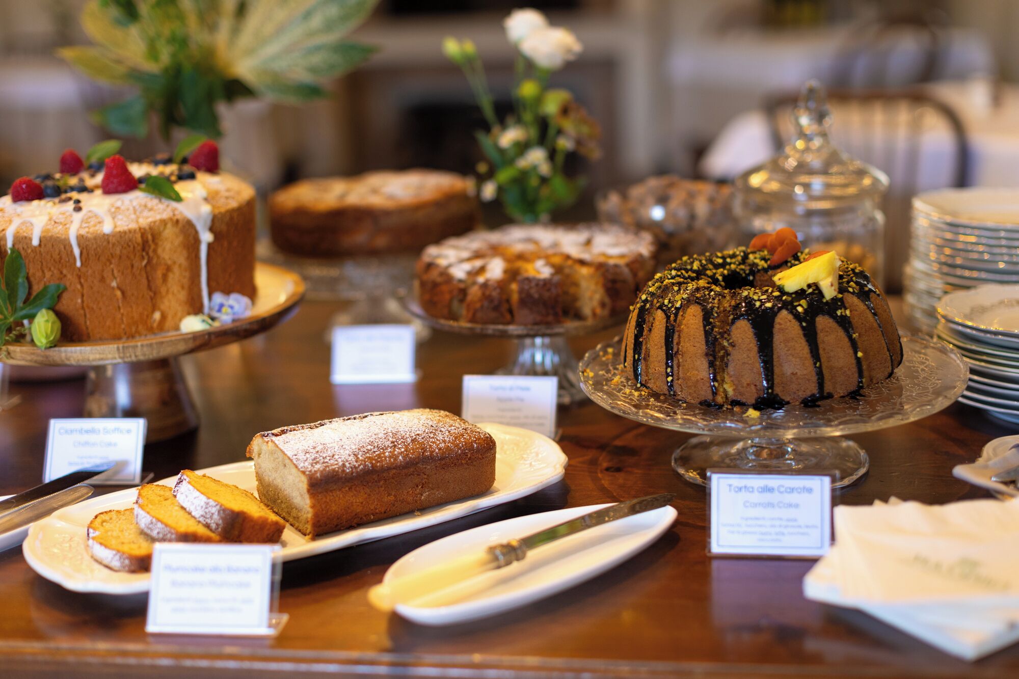 Variedad de pasteles y dulces expuestos sobre una encimera de madera con etiquetas.