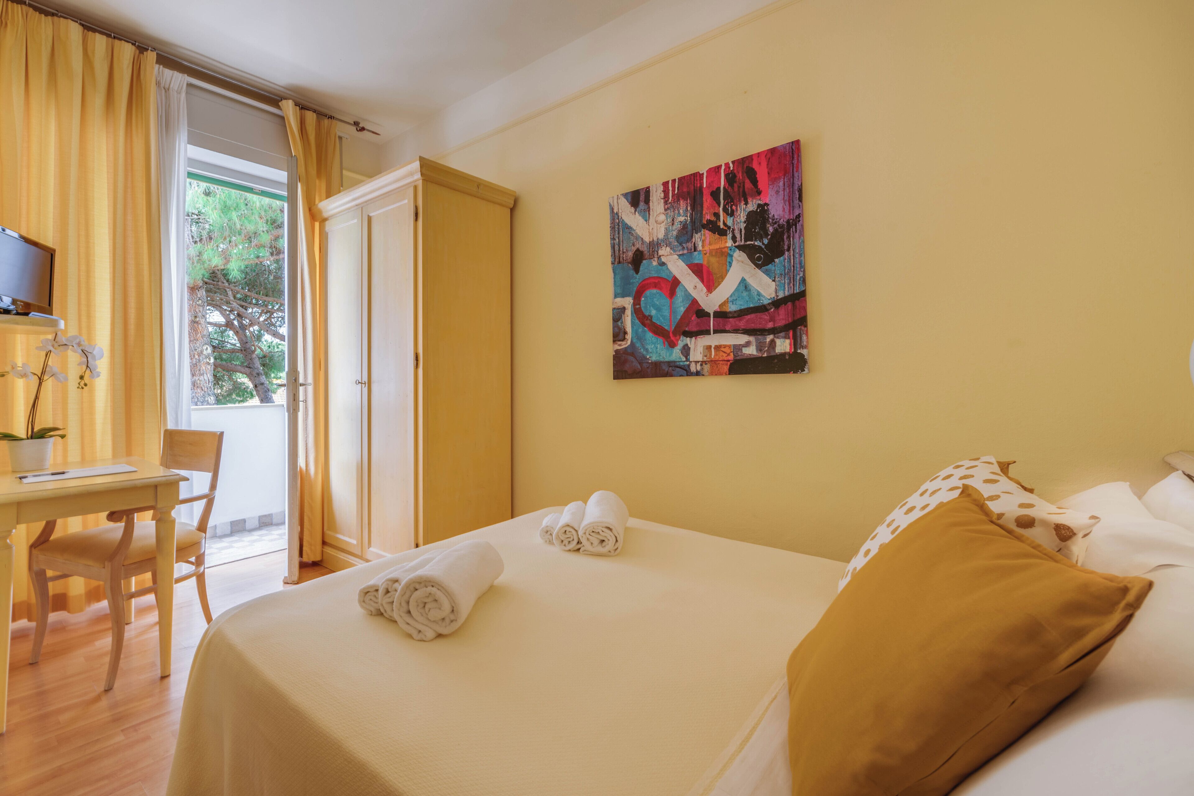 Ein Hotelzimmer mit Bett, Schreibtisch, Stuhl und einem Bild an der Wand.