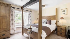 A bedroom with a wooden bed frame, a nightstand with a lamp, and a window with curtains.