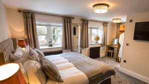 A bedroom with a large bed, a bedside table, a lamp, a radiator, a globe, and a TV mounted on the wall.