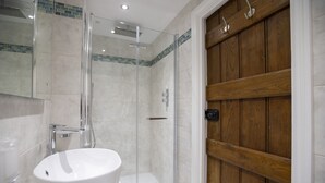 A bathroom with a glass-enclosed shower, a white sink, and wooden paneling on the wall.