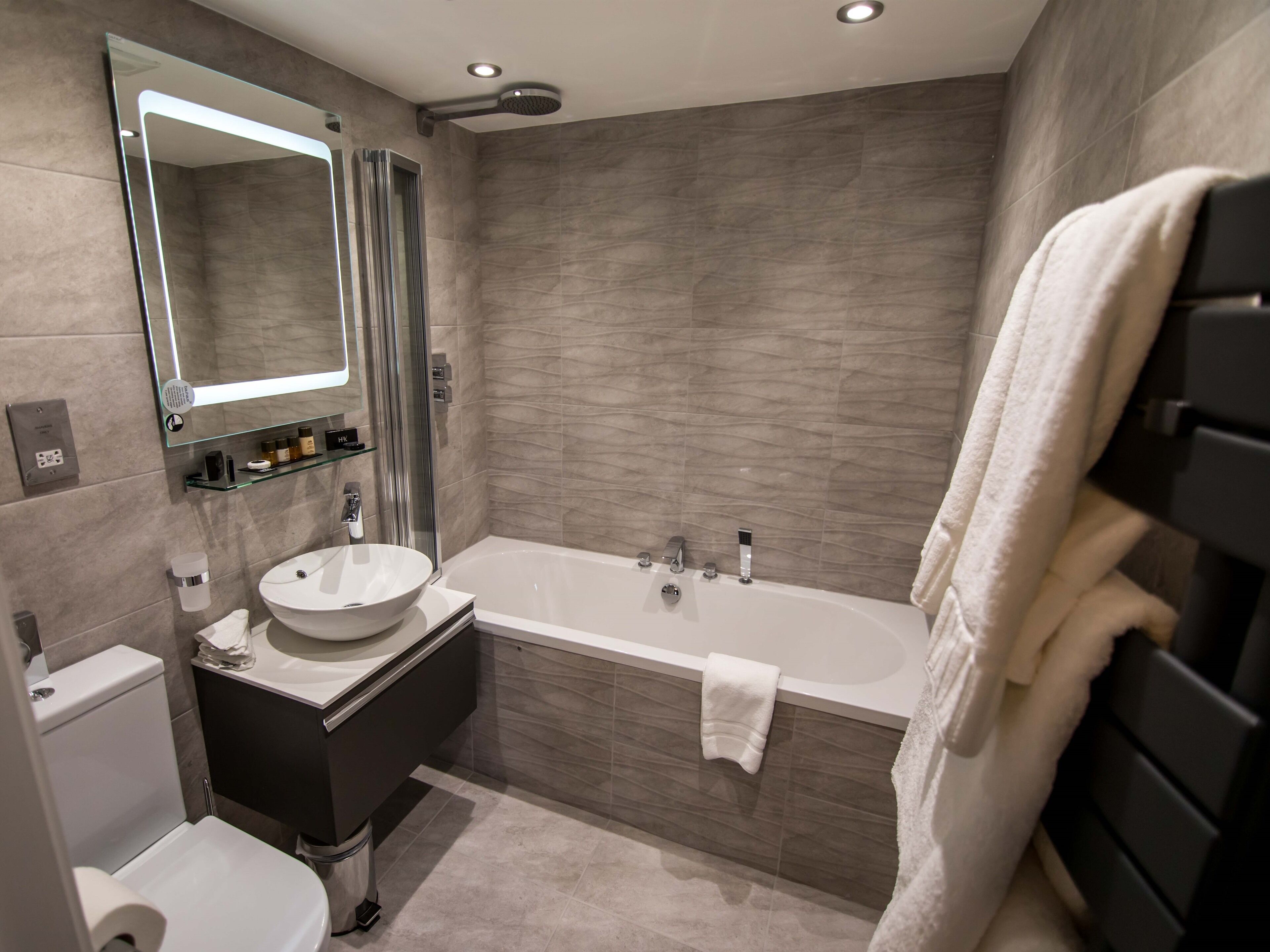 A modern bathroom with a freestanding bathtub, a glass-enclosed shower, and a vanity with a sink and mirror.