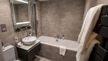 A modern bathroom with a freestanding bathtub, a glass-enclosed shower, and a vanity with a sink and mirror.