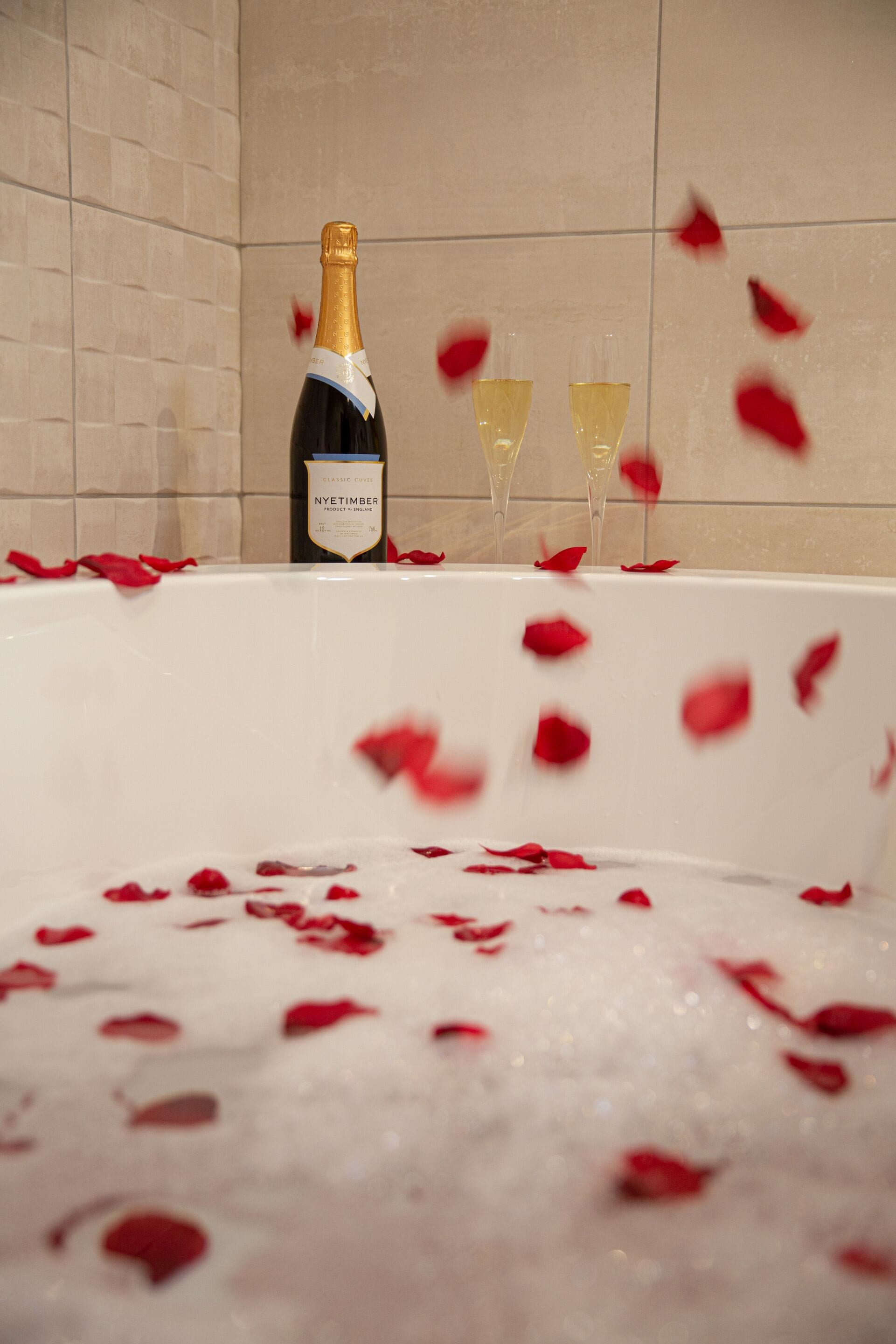 A bathtub filled with rose petals and champagne.