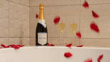 A bathtub filled with rose petals and champagne.