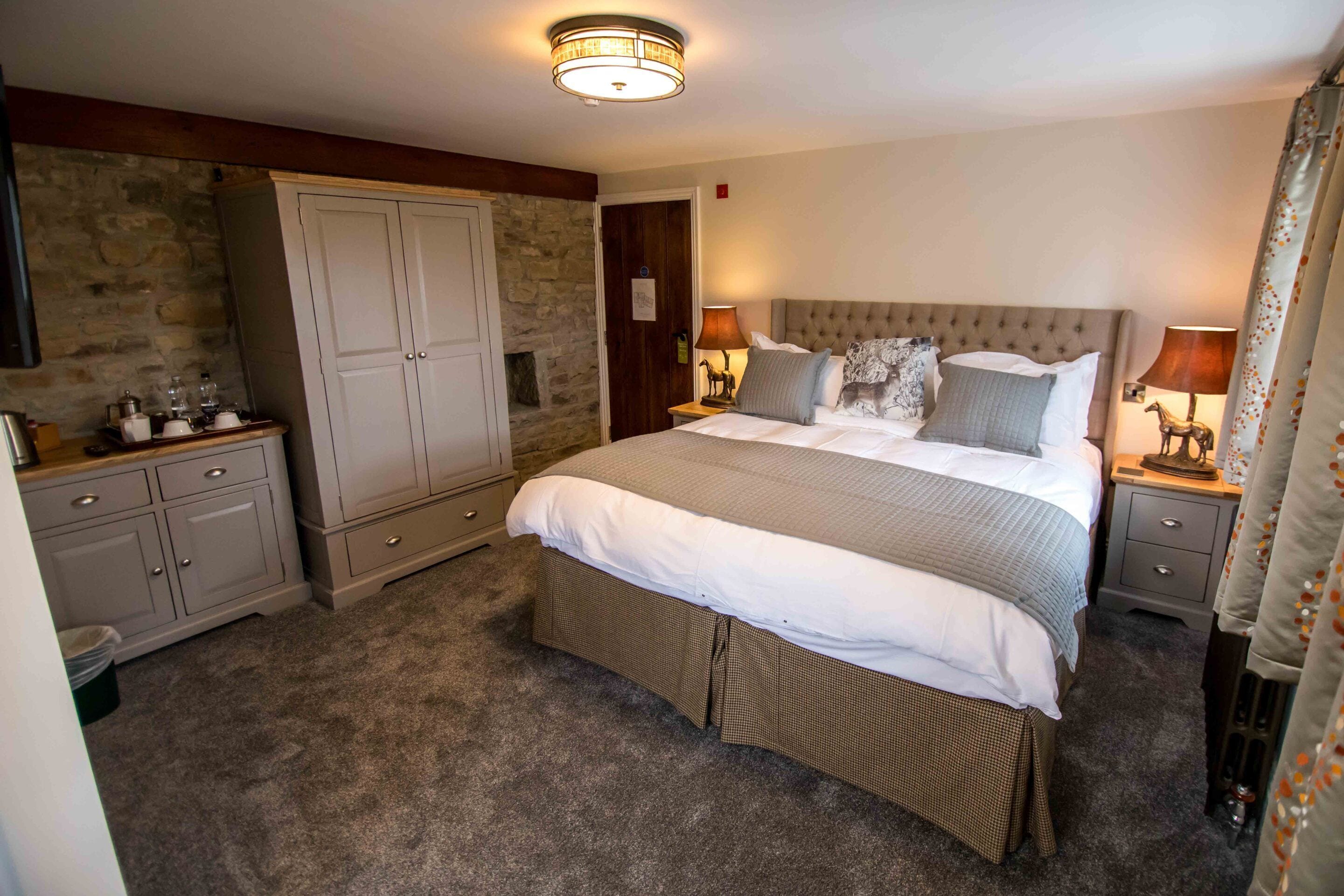 A bedroom with a large bed, a wardrobe, a nightstand, and a lamp.