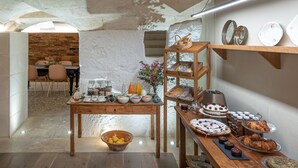 A breakfast buffet with various food items and a rustic interior with exposed brick walls and wooden furniture. - Hotel Boutique Can Sastre (Ciutadella de Menorca)