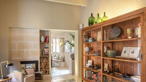 A cozy living room with a fireplace, a bookshelf, and a patterned floor. - Hotel Boutique Can Sastre (Ciutadella de Menorca)