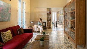 A spacious living room with a red sofa, a wooden coffee table, and a glass cabinet. - Hotel Boutique Can Sastre (Ciutadella de Menorca)