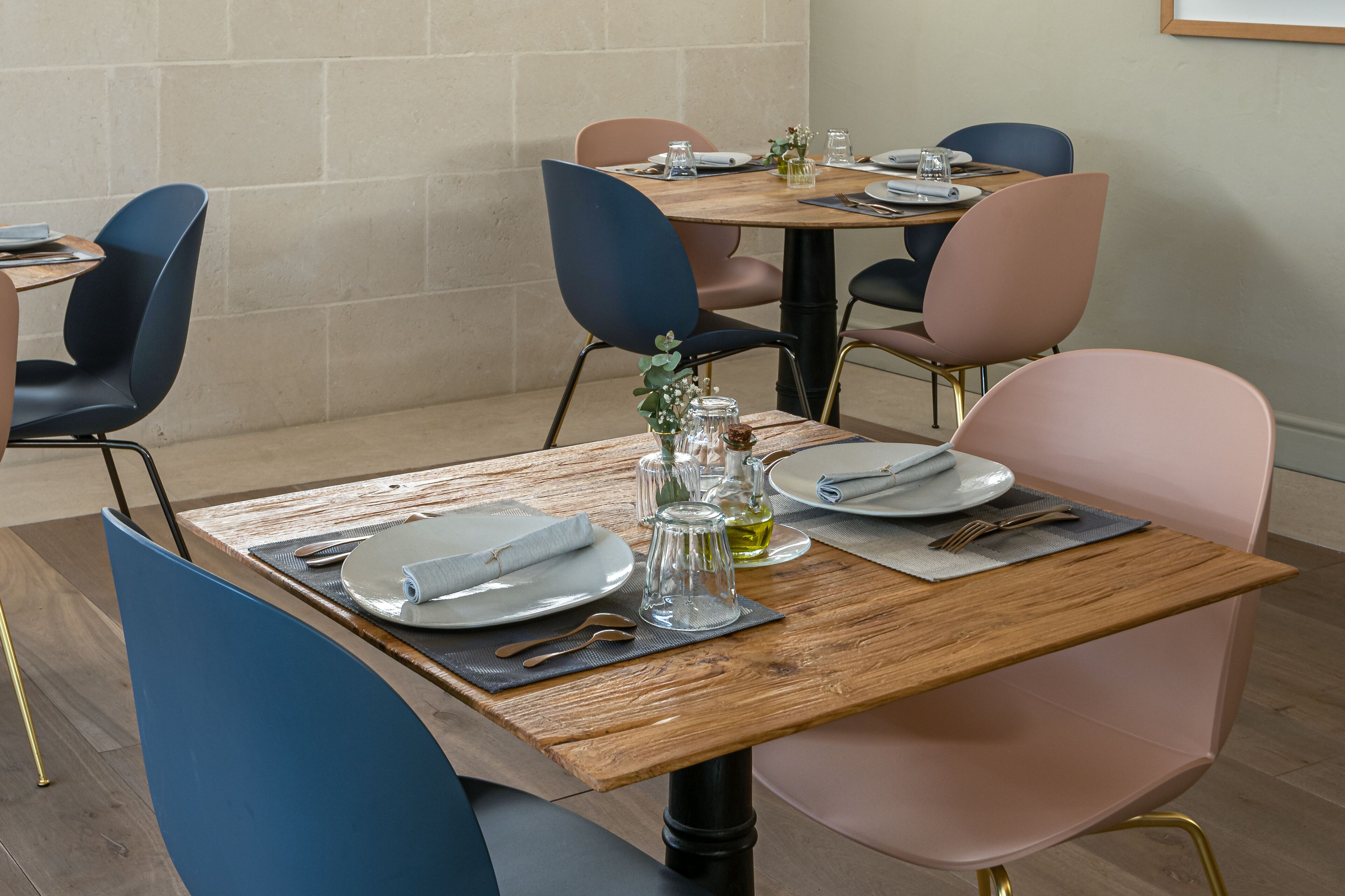 A dining area with a wooden table set for two, surrounded by modern chairs.