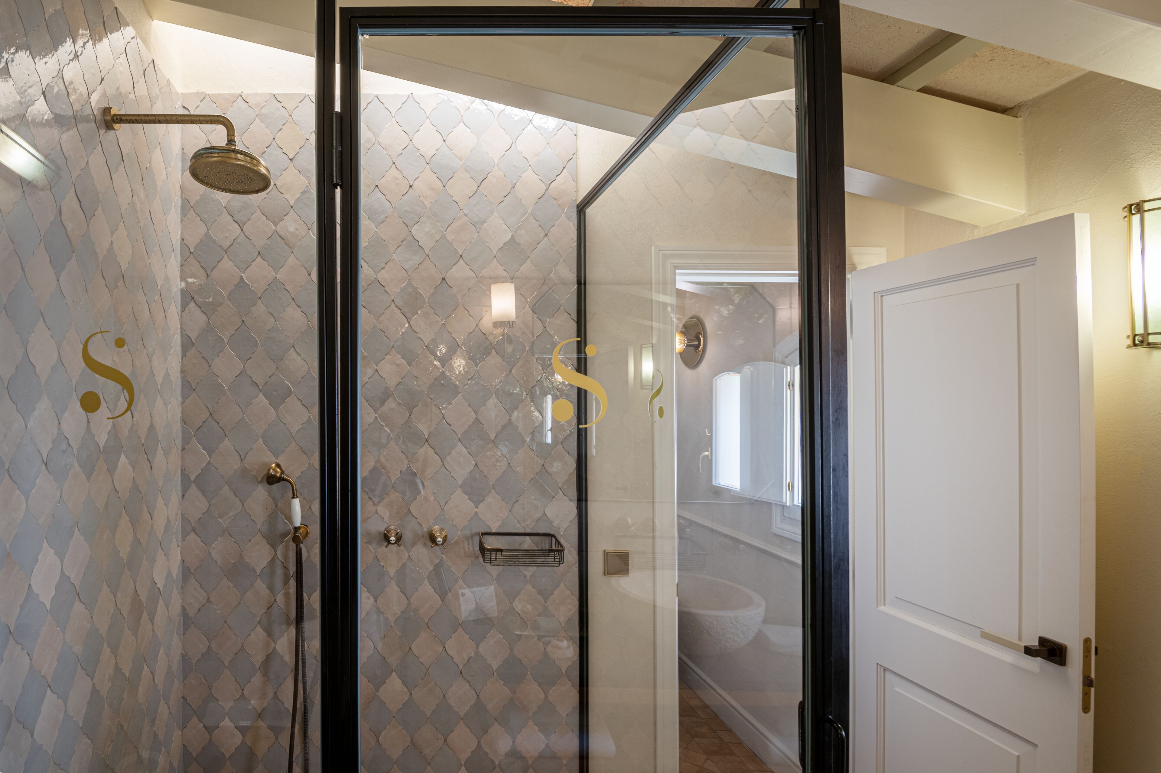 Un baño moderno con cabina de ducha de vidrio, pared con azulejos y puerta blanca.