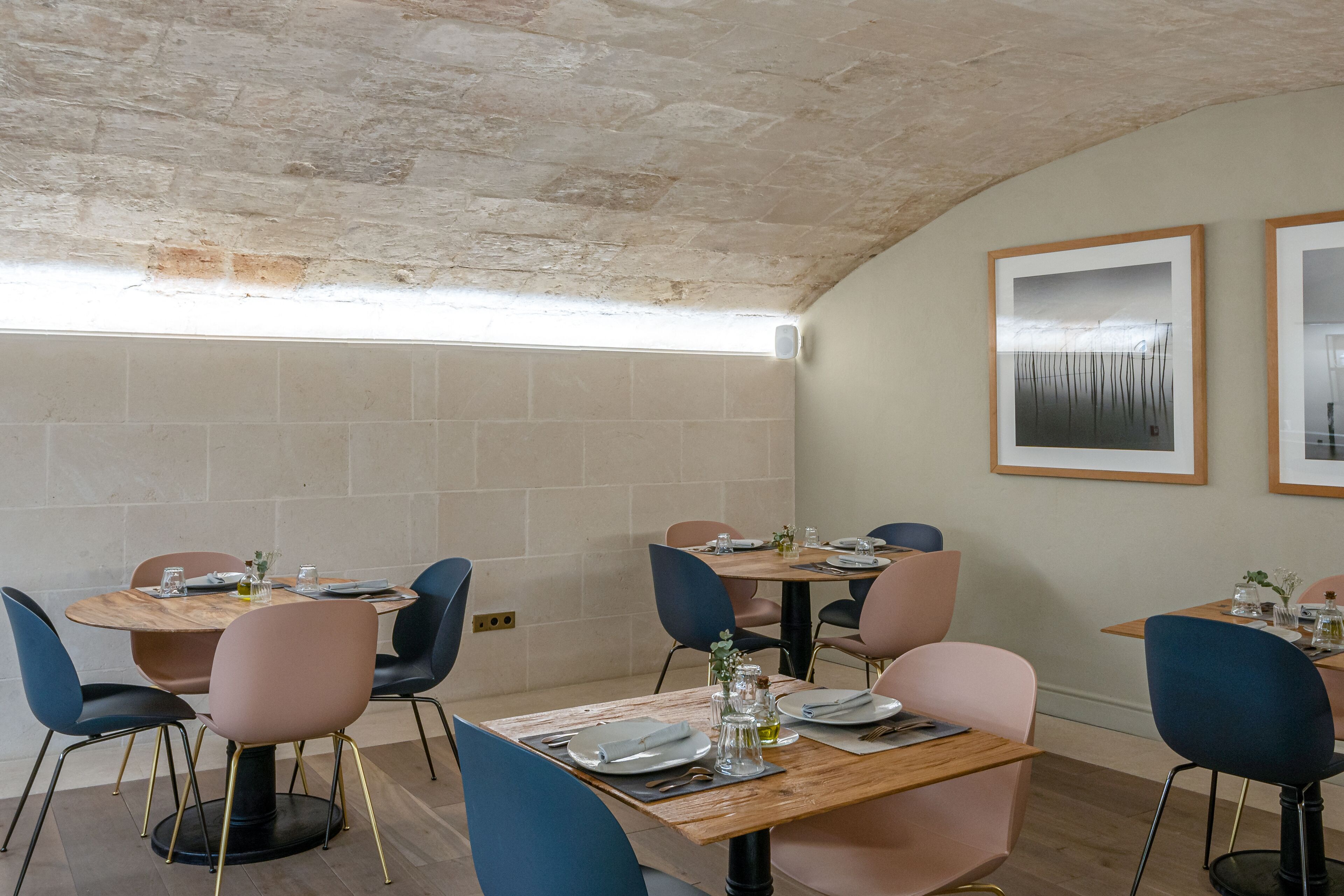 A dining area with round tables, chairs, and framed artwork on the walls.