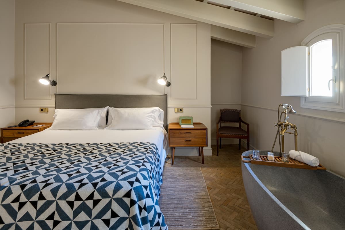 Une chambre à coucher comprenant un lit, des tables de chevet, une commode, une chaise, une coiffeuse avec un miroir et une fenêtre.