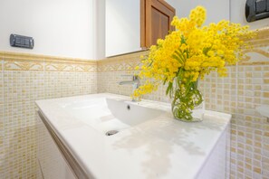 Une salle de bain avec un lavabo blanc, des carreaux à motifs jaunes et un meuble en bois.