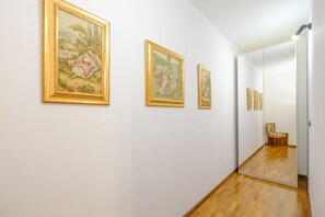 Un couloir avec trois tableaux encadrés accrochés au mur, un plancher en bois et un miroir qui reflète une partie de la pièce.