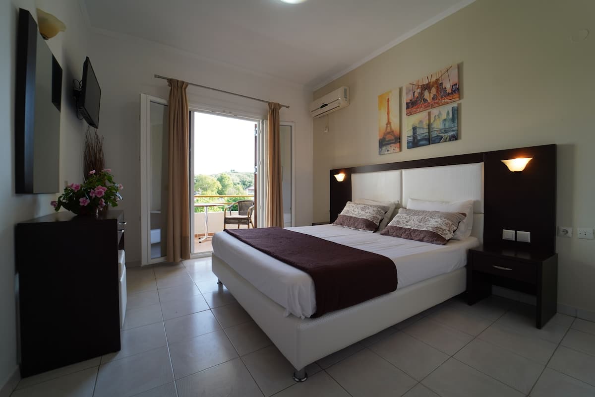 Quarto com uma cama grande, mesa de cabeceira, escrivaninha e uma cadeira.