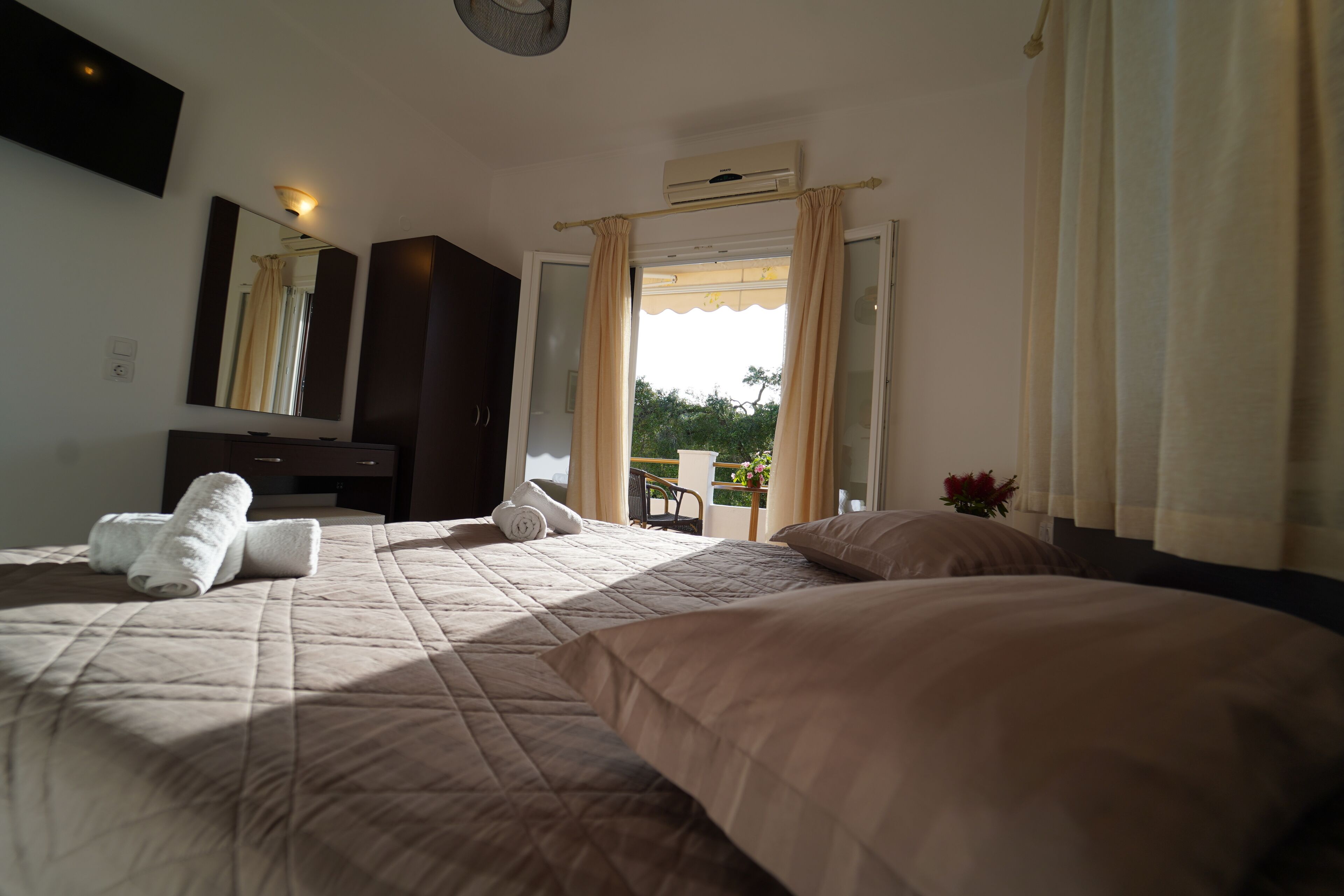 A hotel room with a large bed, a desk, a chair, and a window with curtains.
