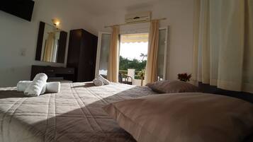 A hotel room with a large bed, a desk, a chair, and a window with curtains.