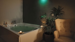 A room with a bathtub, a potted plant, and a chair. - Villa Apollo Parga (Parga)