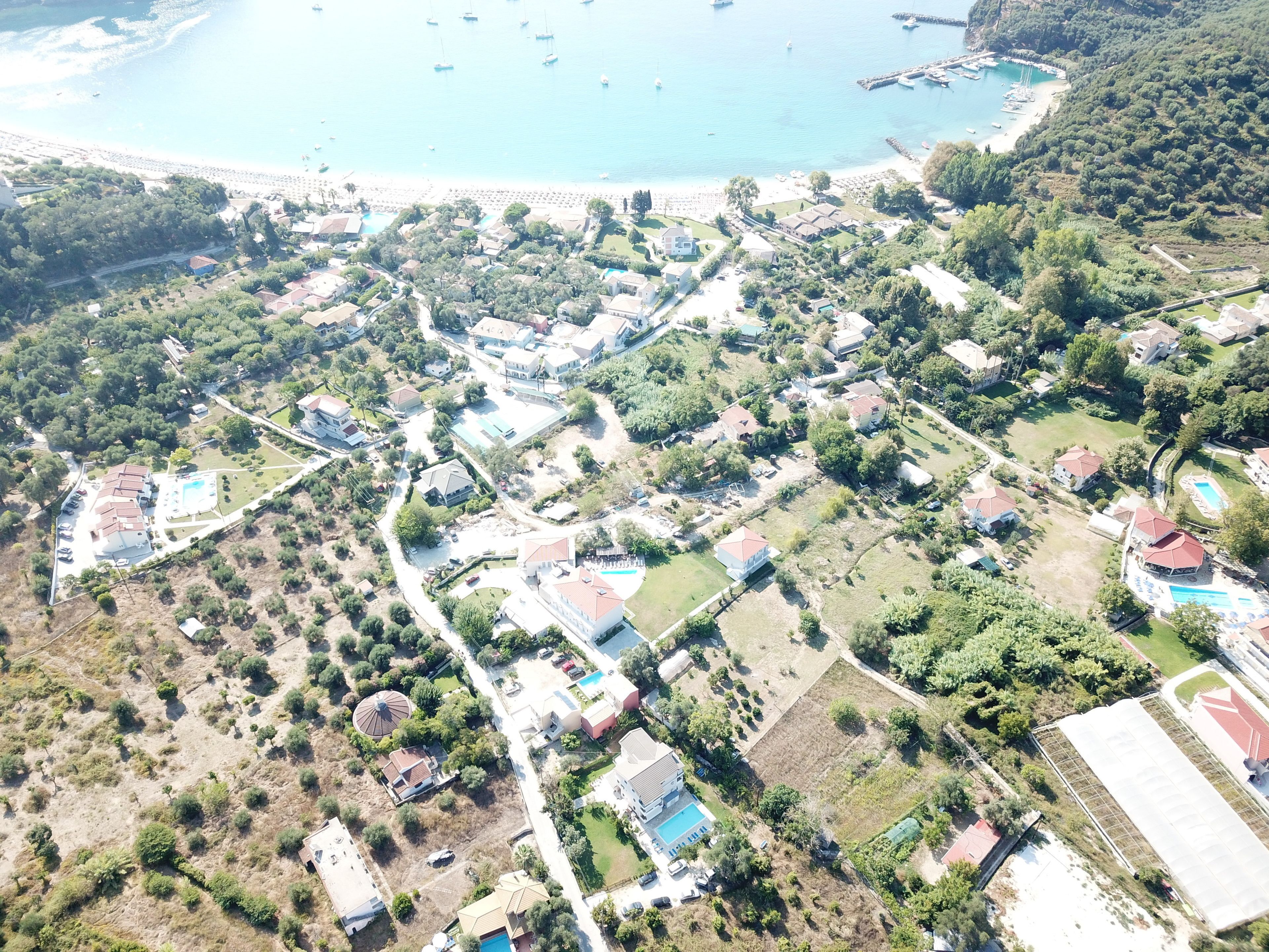 Vista aérea de una zona residencial costera con casas, una playa y barcos.